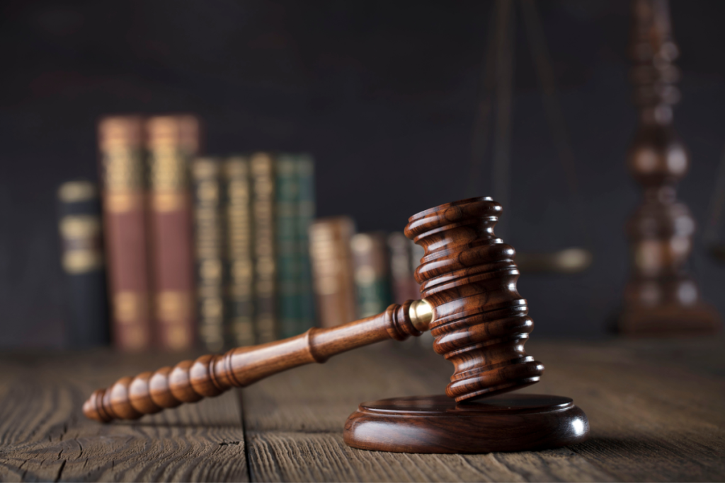 Gavel in foreground with blurred law books and pendulum of justice in the background