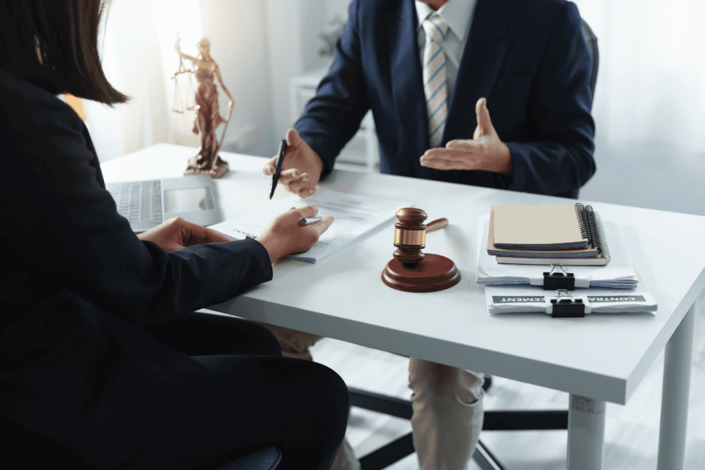 Someone speaking with an attorney at a table with a gavel and justice statue